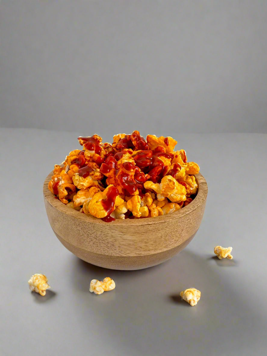 Wooden bowl filled with spicy popcorn on a white background